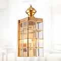 Full copper wall lamp with glass shade and gold finish on a brick balcony wall