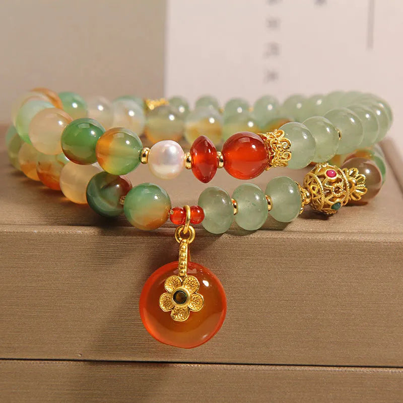 Women's peacock green agate double ring bracelet with safety buckle and rhinestones on a wrist.