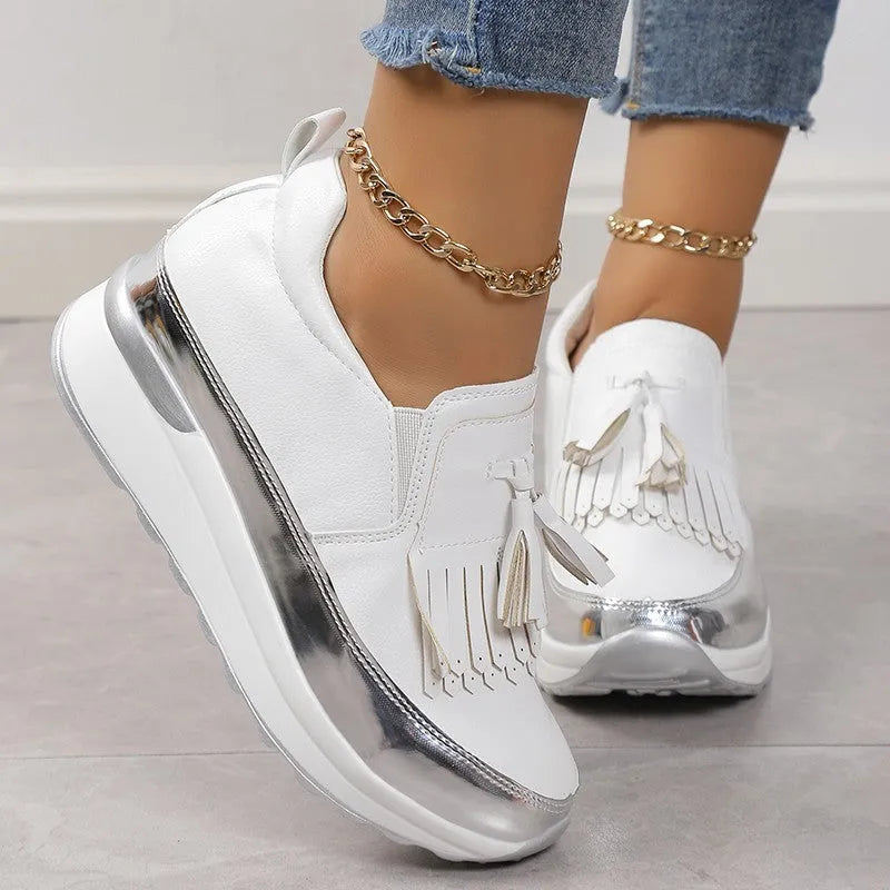 Black women's platform shoes with a tassel on the front and a thick muffin wedge heel.