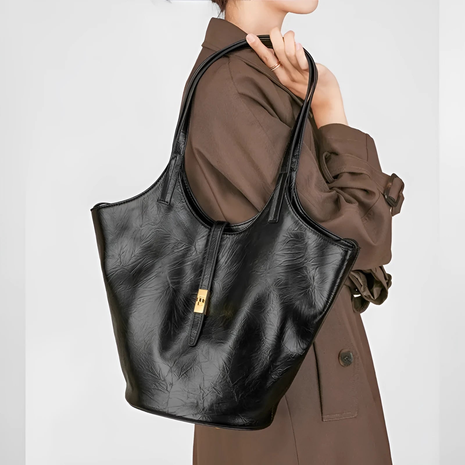 Black genuine leather large capacity bucket bag with visible stitching and crossbody strap on white background