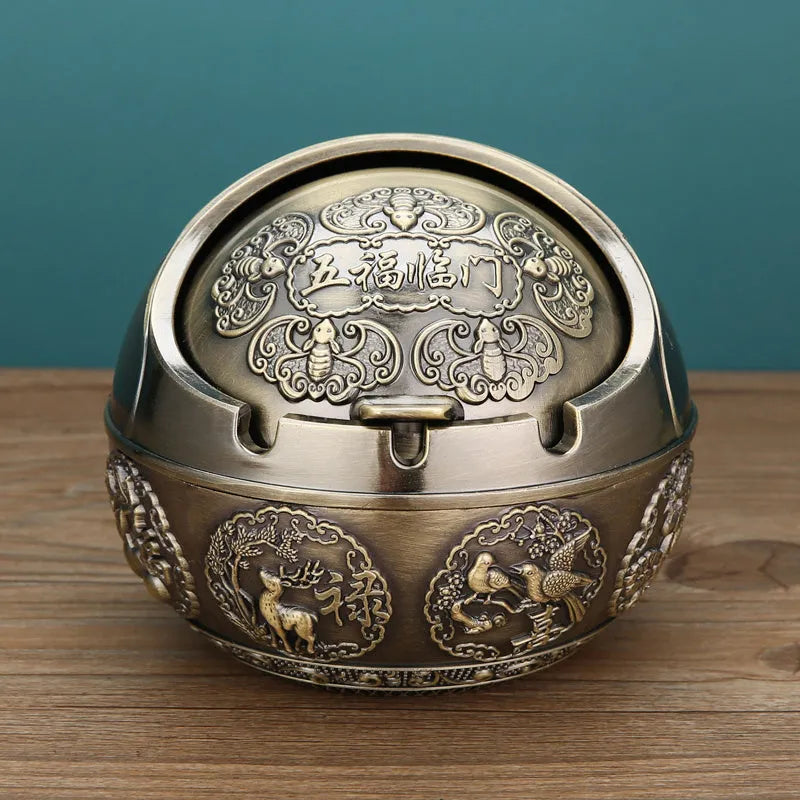 Alloy decorative ashtray in bronze with ornate peacock motif and cigarette extinguishing slot.