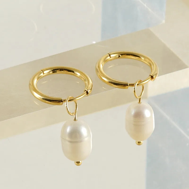 A pair of gold-coloured geometric earrings with a pearl detail, made from stainless steel.