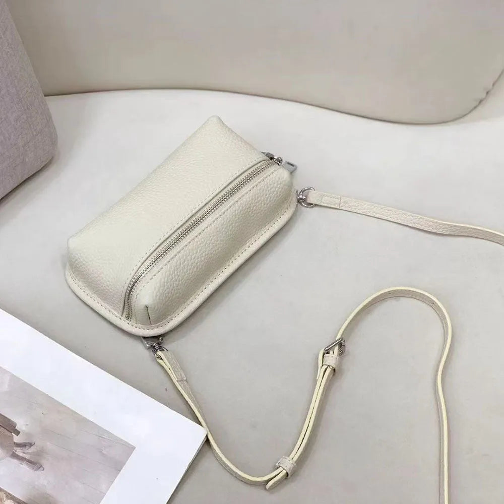 Mini crossbody bag in top grain leather with polyester lining, retractable handle, welt pocket, and solid colour patchwork design.