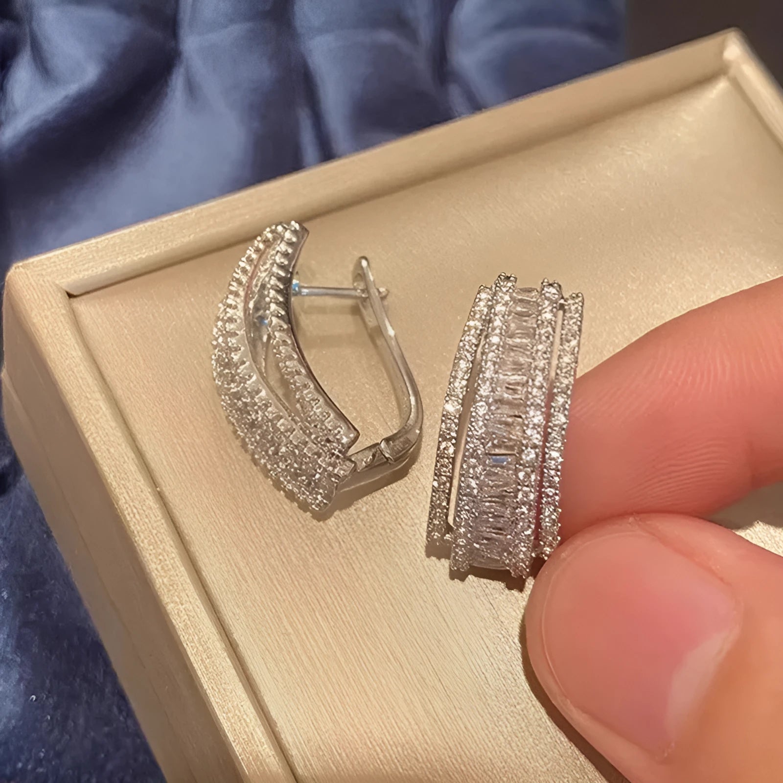 A pair of women's geometric stud earrings in white gold colour with a central inlaid zircon stone.