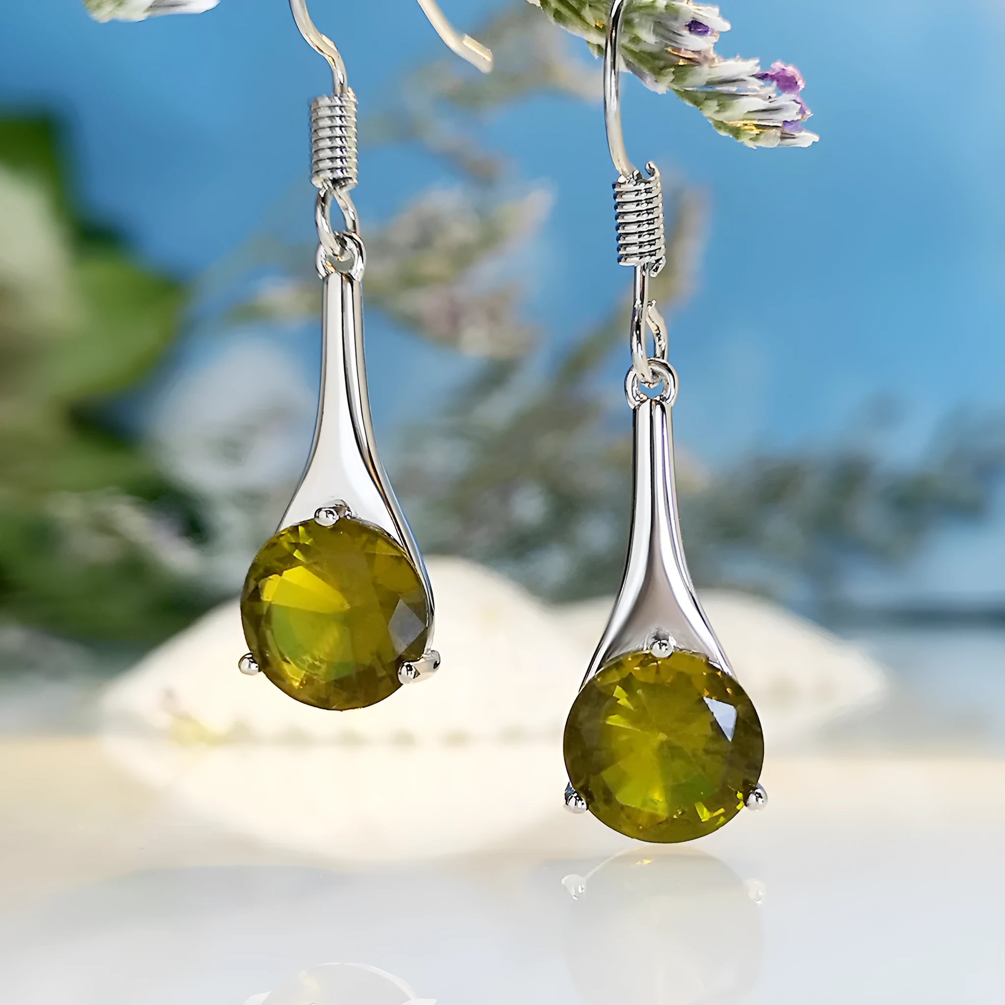 Olive green topaz coloured drop-shaped fashion earrings with a retro style on a white background.