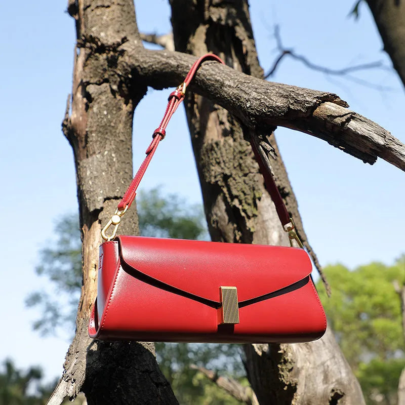 Women's leather cross-body shoulder bag in clamshell design with internal organisers.