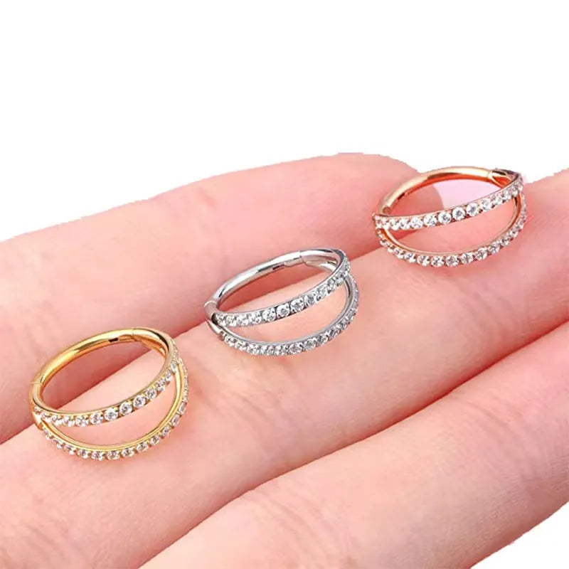 G23 titanium alloy nose ring with monoclinic diamond treatment in gold and steel colour on a grey background.