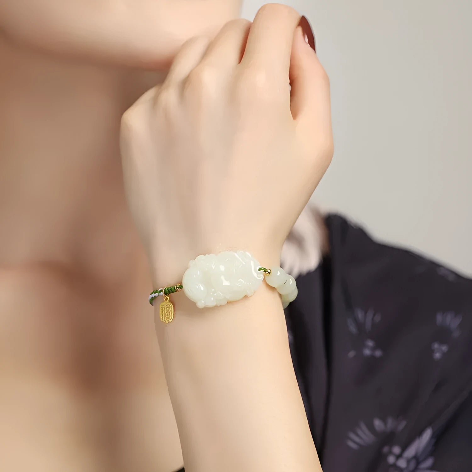 Red rope bracelet with a carved green Hetian jade Rabbit charm and a small S925 silver card on a cotton cord.