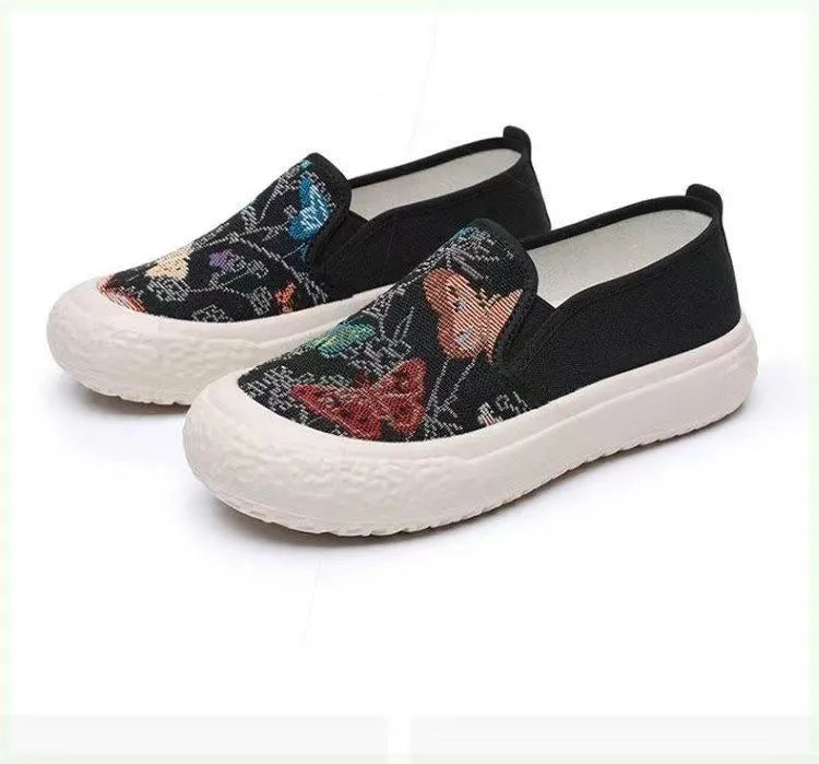 Women's black and white canvas slip-on shoes with round toe and decorative stitching.
