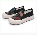 Women's black and white canvas slip-on shoes with round toe and decorative stitching.