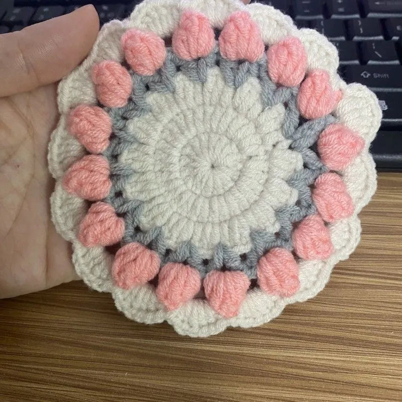 Handmade woven floral coaster in cotton and linen on a wooden table