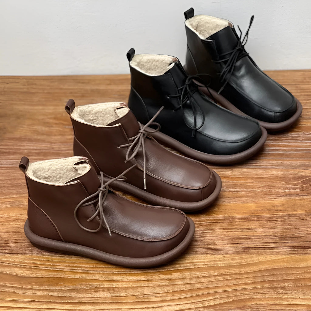 Women's black cowhide winter boots with flat heel and round toe on neutral background
