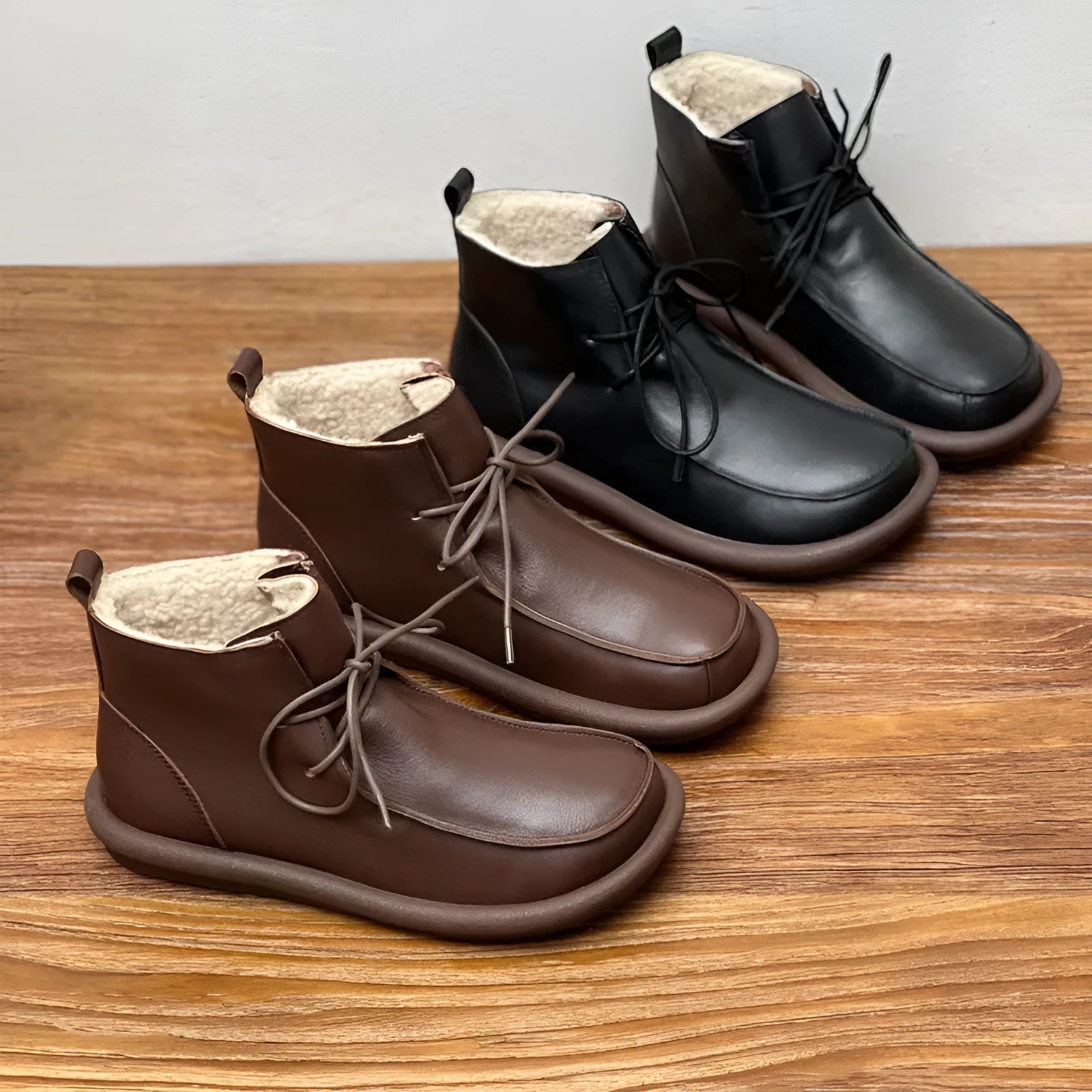 Women's black cowhide winter boots with flat heel and round toe on neutral background