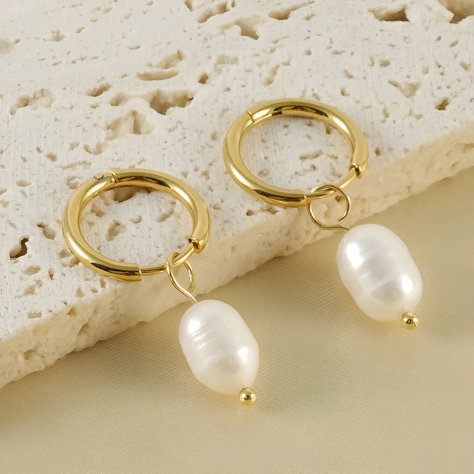 A pair of gold-coloured geometric earrings with a pearl detail, made from stainless steel.