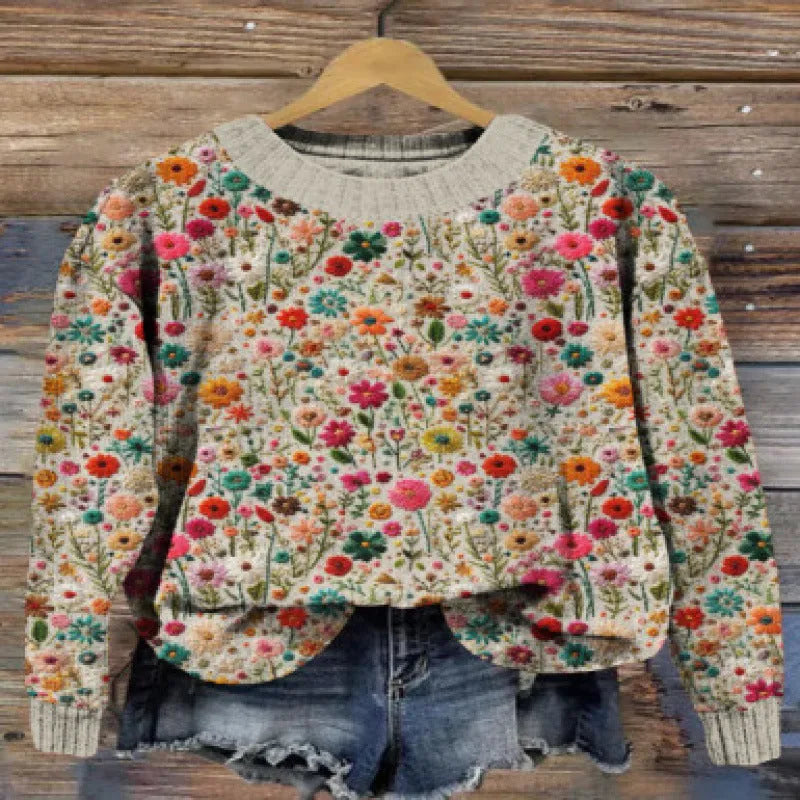 A round neck sweater with a colourful digital floral print, shown on a hanger.