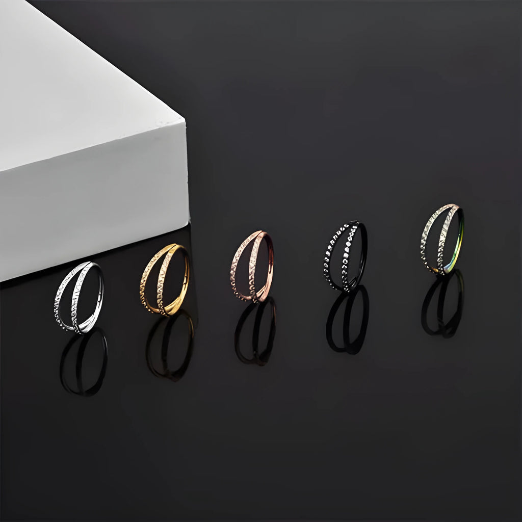 G23 titanium alloy nose ring with monoclinic diamond treatment in gold and steel colour on a grey background.