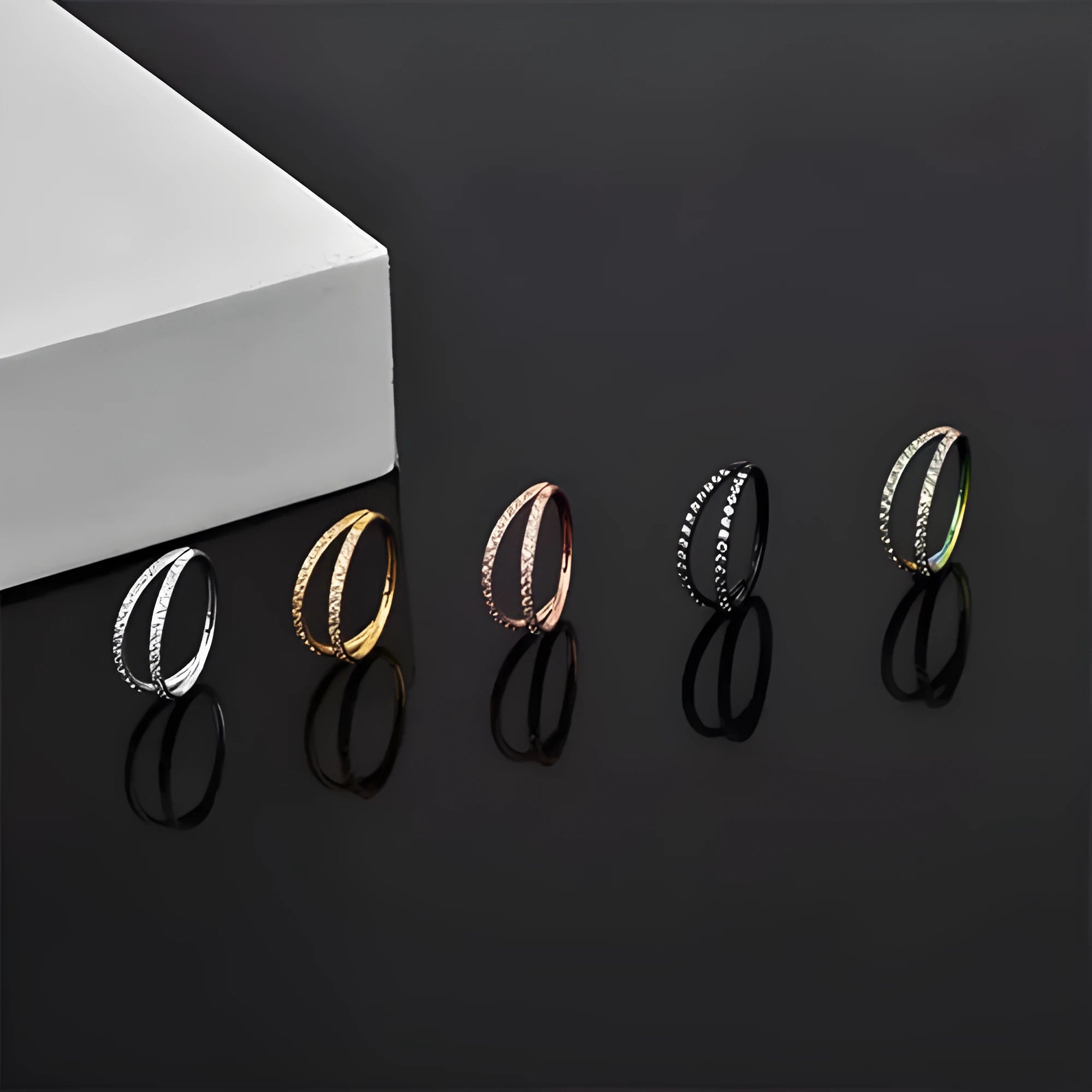 G23 titanium alloy nose ring with monoclinic diamond treatment in gold and steel colour on a grey background.