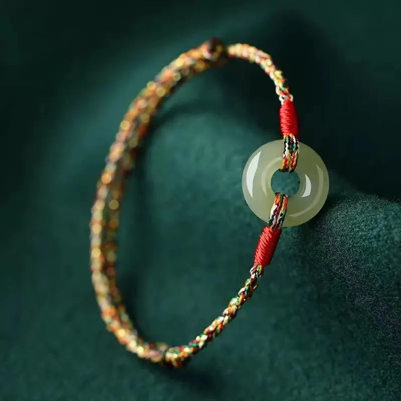Close-up of a colourful woven rope bracelet with a silver peace buckle clasp on a wrist.