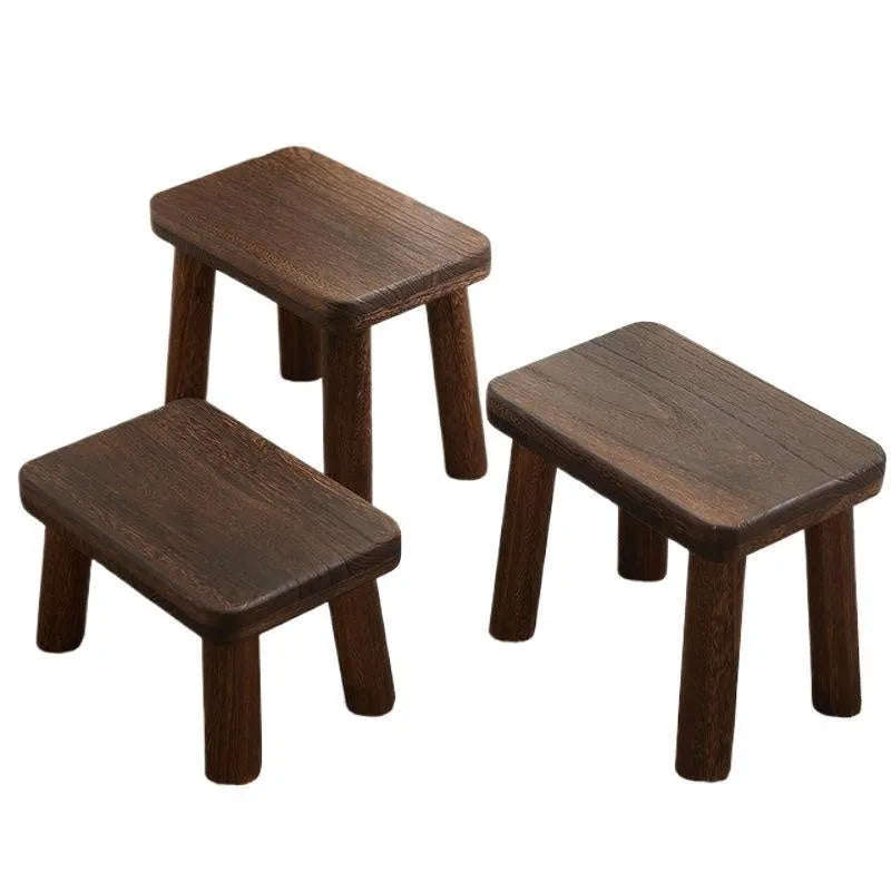 Solid wood shoe changing stool with a distressed finish and angular bracket frame.