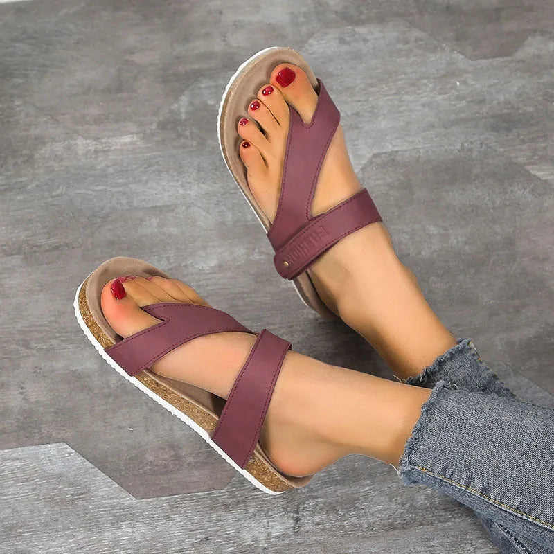 Flat toe ring flip-flops with a thick foam sole in a solid blue colour on a sandy beach.