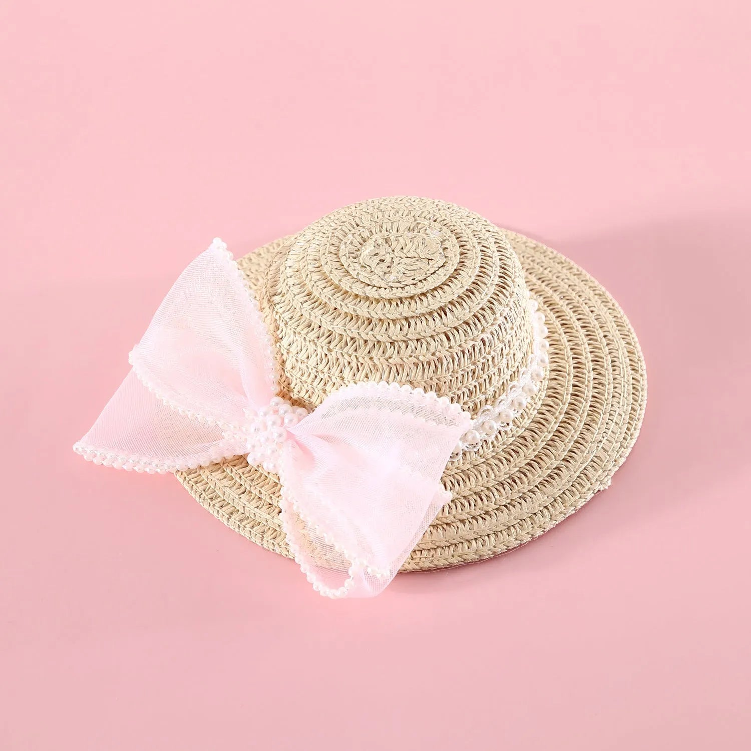 Cat wearing woven straw hat with pearl bow decoration in princess style
