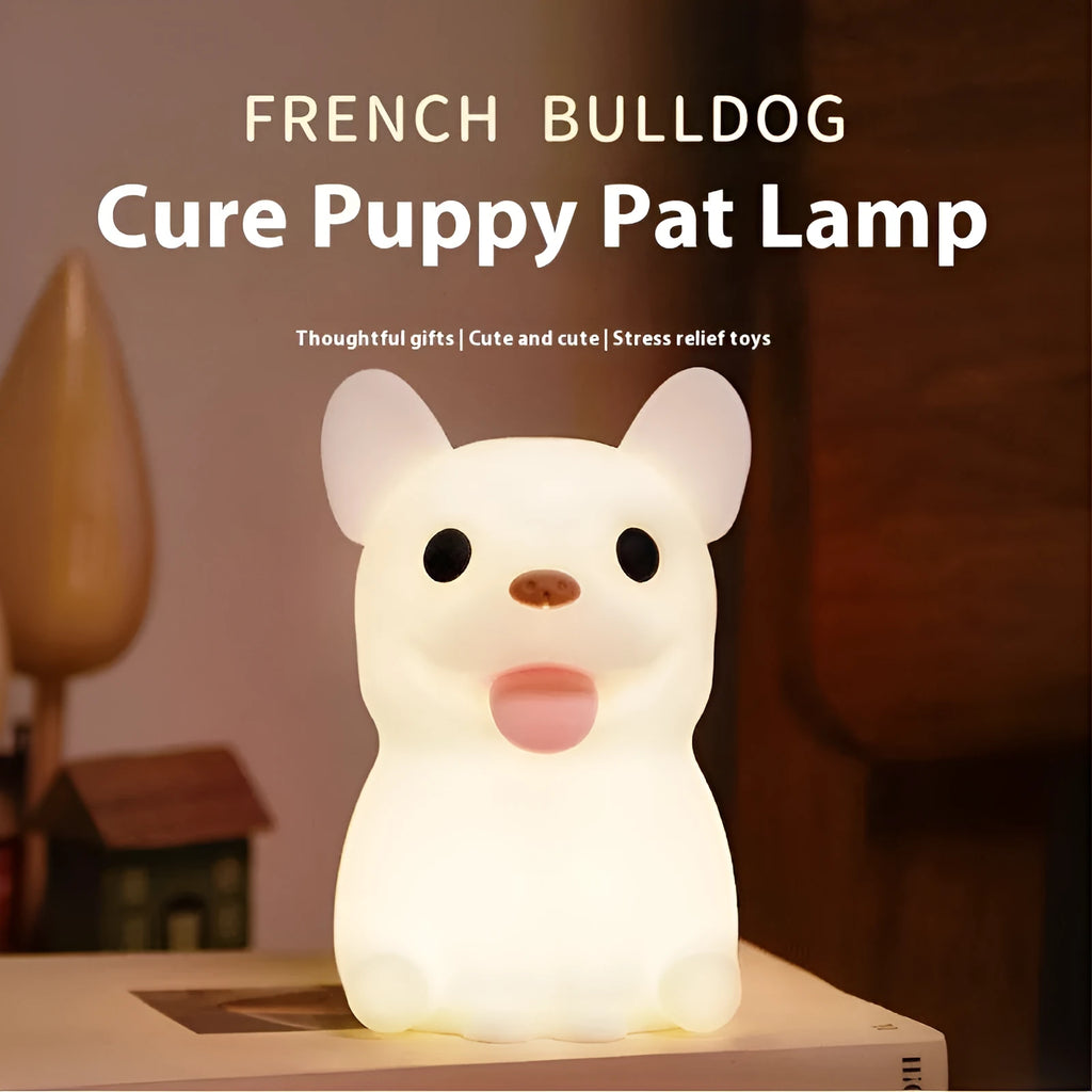 Soft silicone animal or cartoon-themed USB night light with dimming function on a bedside table.