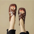 Women's glossy patent leather sandals with a square toe and low heel on a solid colour background.