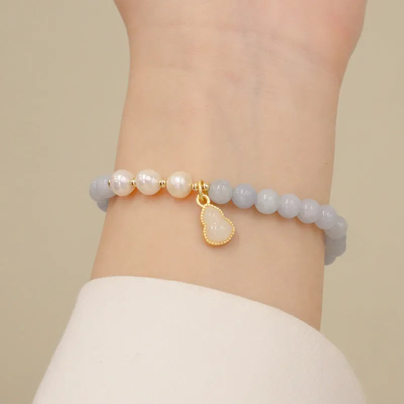 Gold plated bracelet with a detailed artificial crystal charm pendant on a woman's wrist.