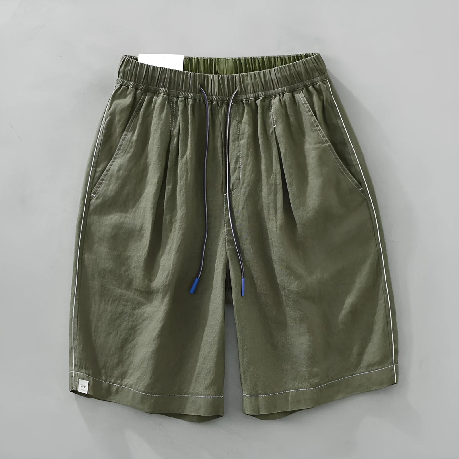 Men's loose fit linen shorts in green, showing straight drooping leg and drawstring waist.