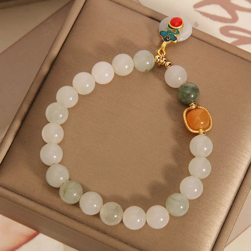 Women's ice jade bracelet with Xiangyun peace buckle and pearl details on a wrist.