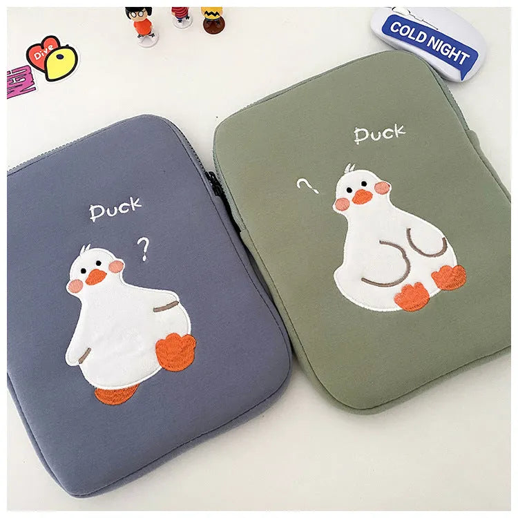 Blue cotton tablet case with embroidered cartoon duck design and a zipper closure, shown next to a green version.