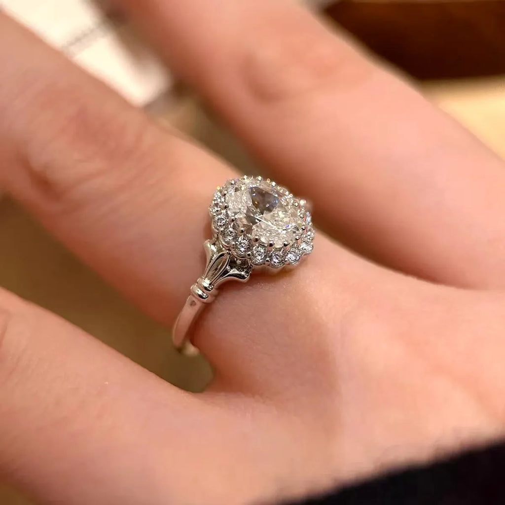 Silver geometric ring with an elliptical diamond centre on a model's hand, showing adjustable opening.