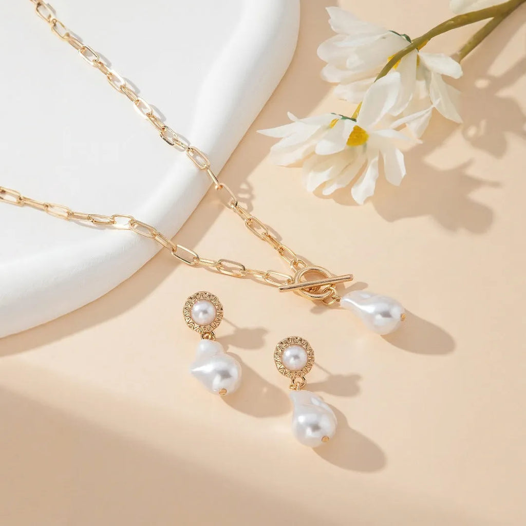Gold-coloured retro baroque pearl necklace and matching ear studs set on a display.