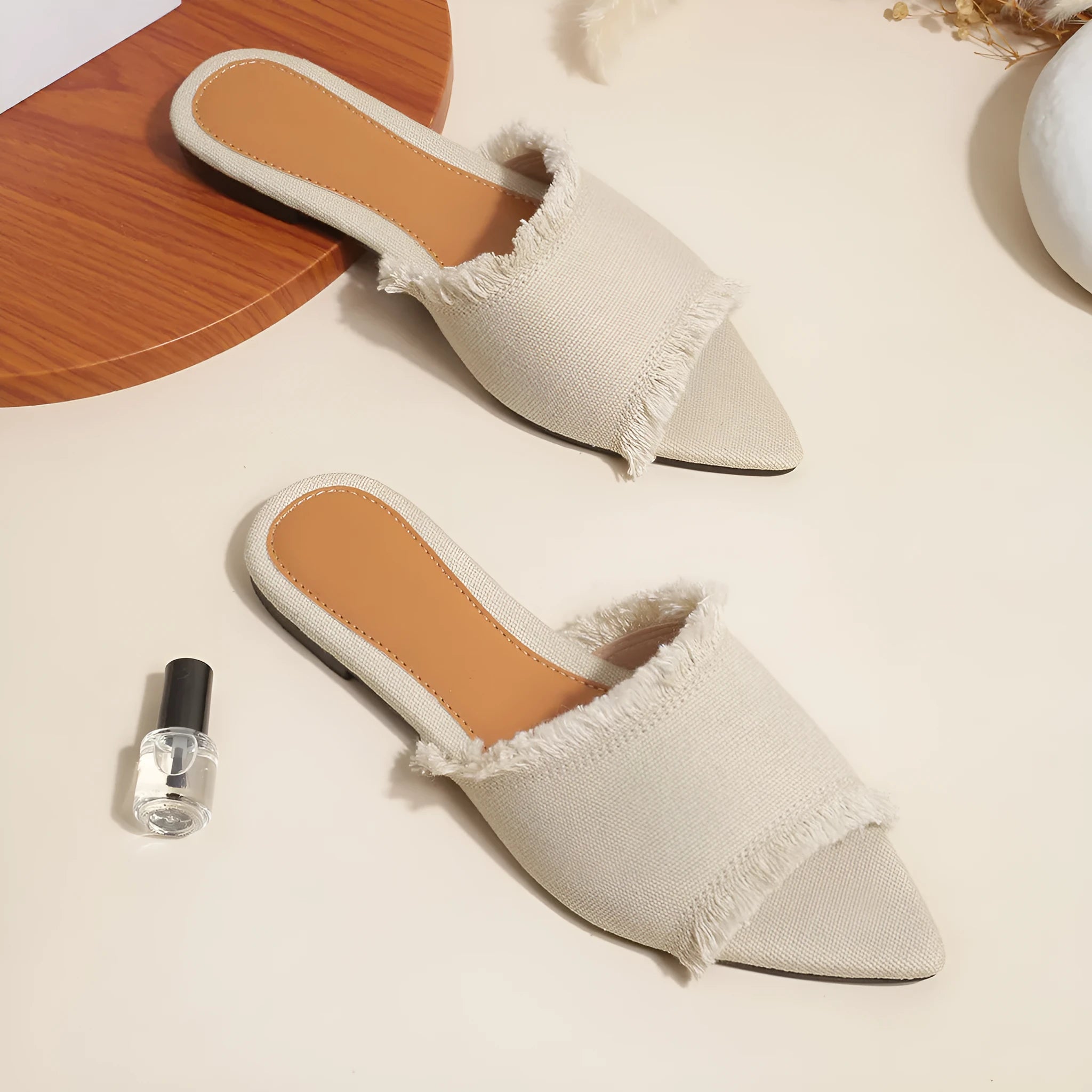 Women's solid colour denim flat slippers with a tassel detail on the front.