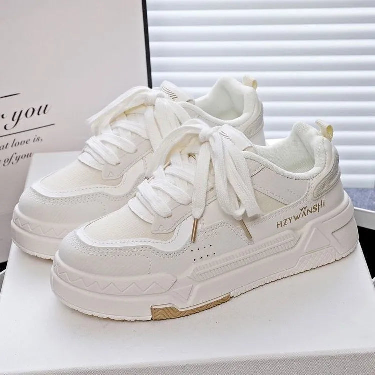 Beige children's lace-up trainers with cross straps over instep and thick rubber sole.