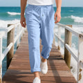 Men's light khaki linen trousers with a drawstring waist and straight leg on a hanger.