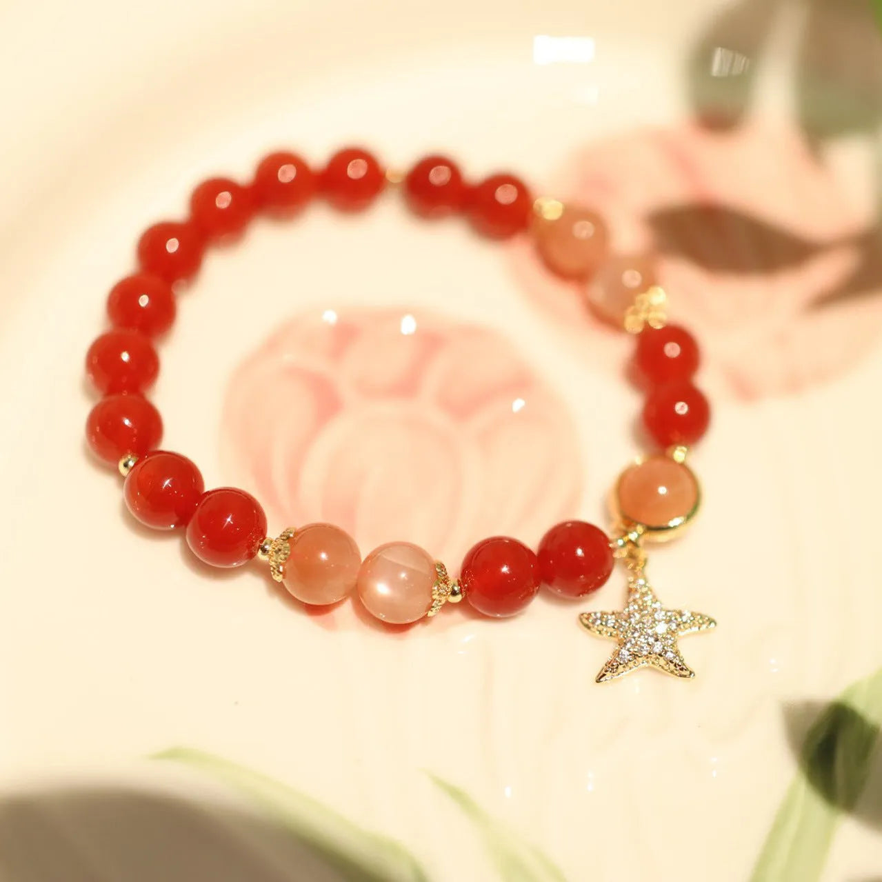 Handmade red agate bracelet with 8mm beads, star and xiangyun patterns, on a wrist.