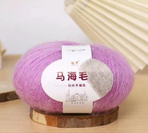 A ball of mohair yarn in a selected colour next to a hand-woven scarf example, showcasing the DIY kit.