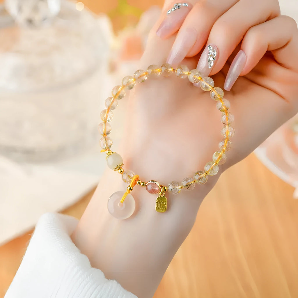 Gold rutilated quartz bracelet with safety buckle and geometric blessing card pendant.