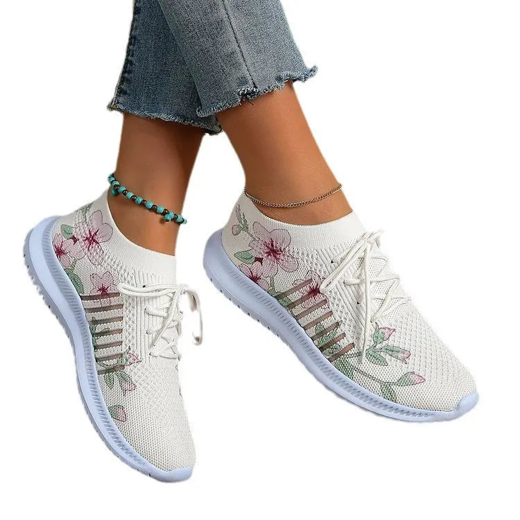 Women's milky white mesh flyknit running shoes with flat heel and rubber sole on grey background