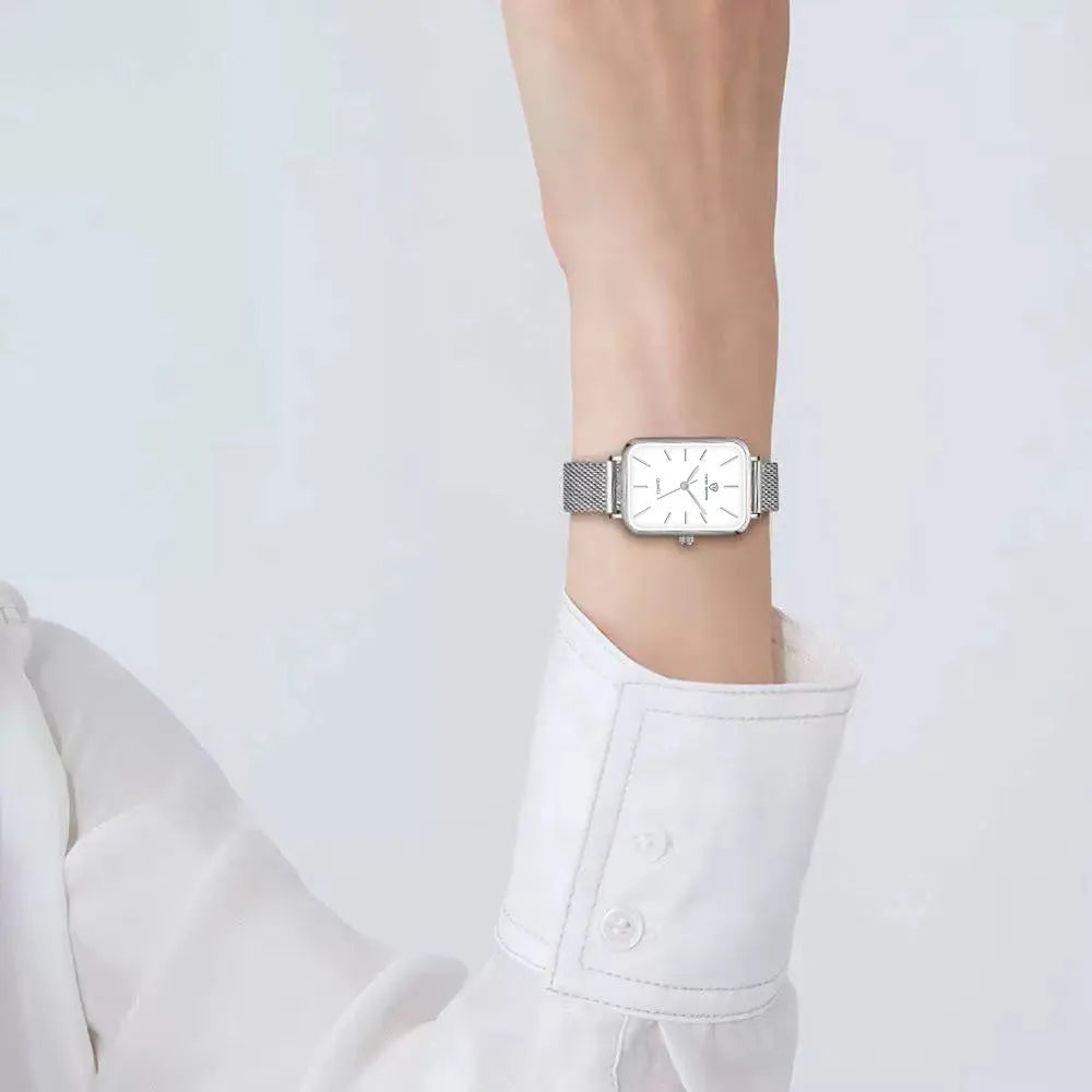 Women's rose gold waterproof quartz watch with woven steel strap on wrist.