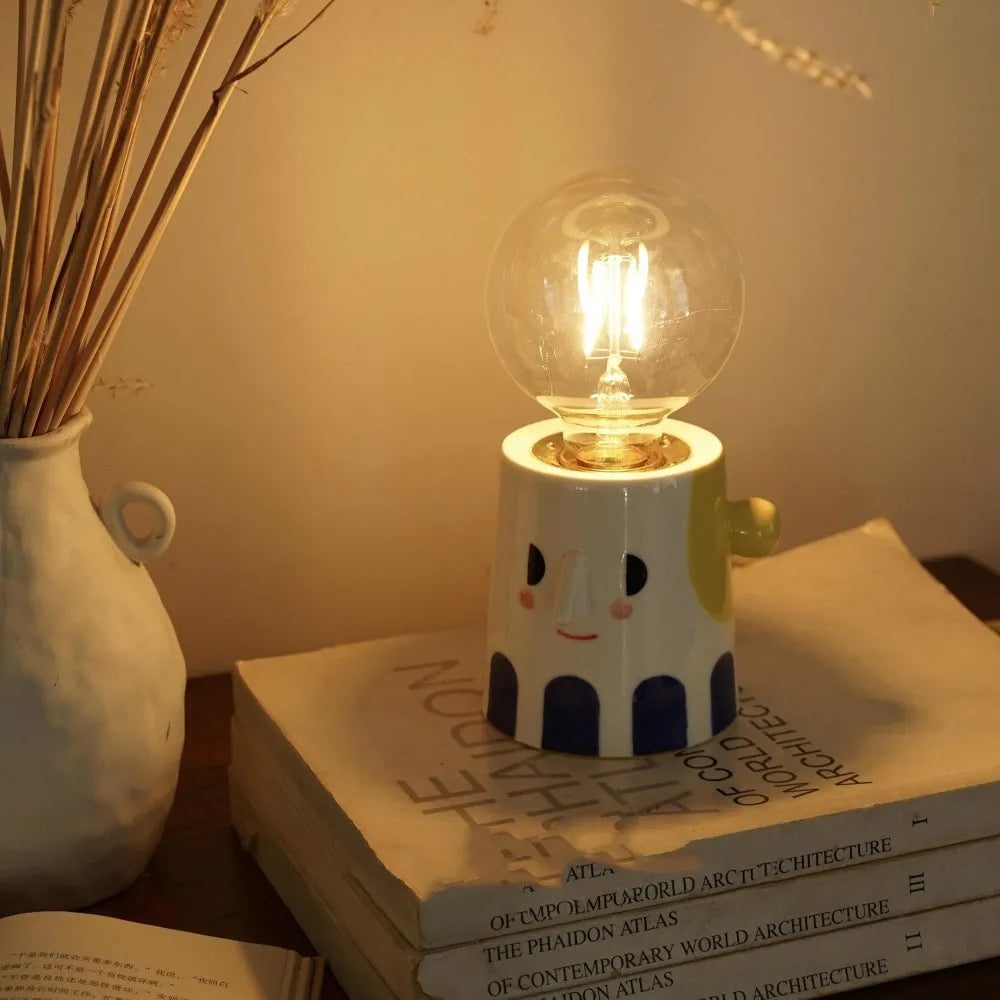 Handmade ceramic bedside lamp with a white ball headlight on a wooden table.