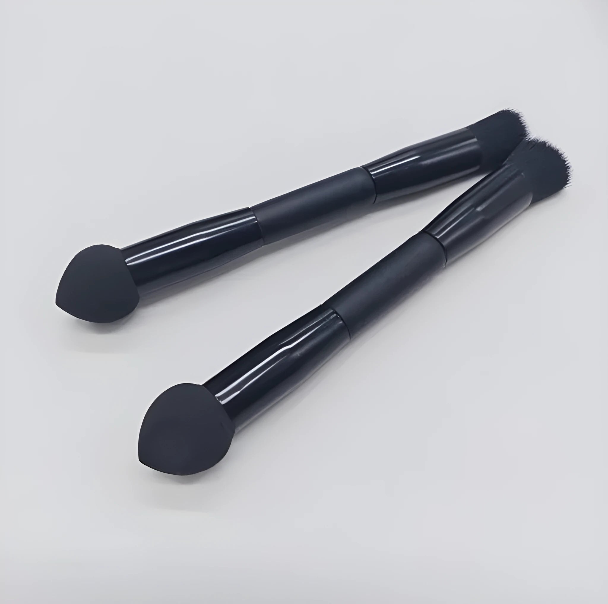 Black double-headed concealer brush with sponge end and tapered brush end on wooden handle