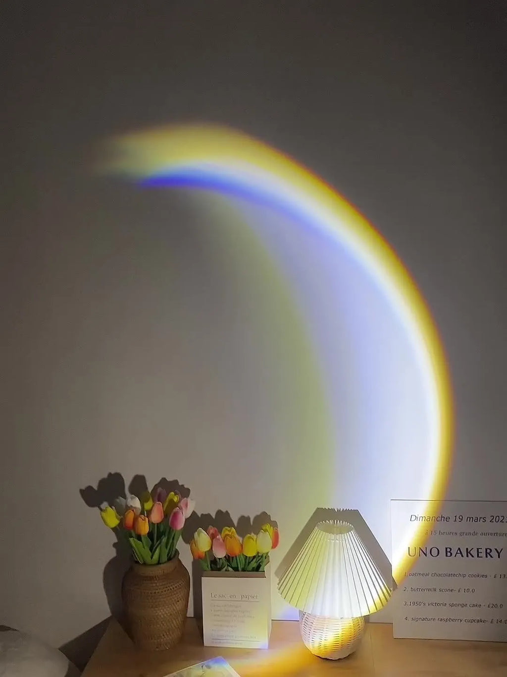 INS USB Moon Lamp LED projector on a table projecting rainbow light onto a wall.