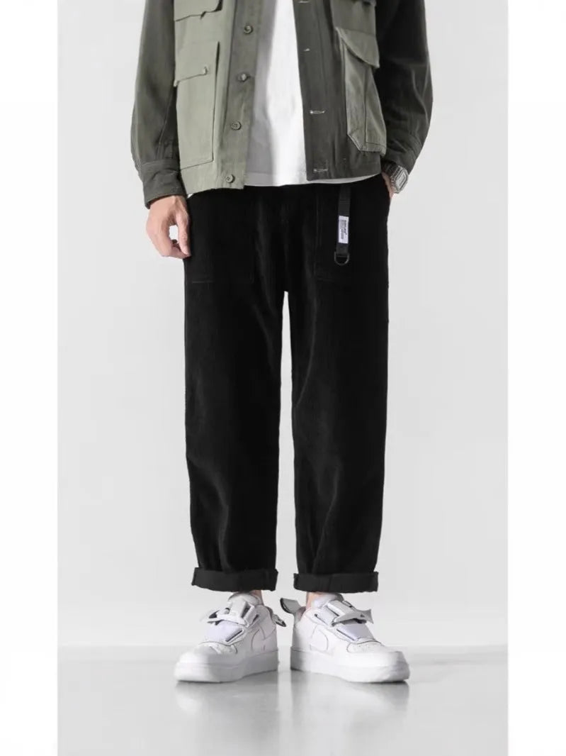 Man wearing loose straight tapered trousers in dark grey, showcasing the straight leg and relaxed fit.