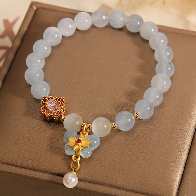 Women's adjustable bracelet with an aquamarine crystal butterfly pendant and rhinestone details on a metal chain.