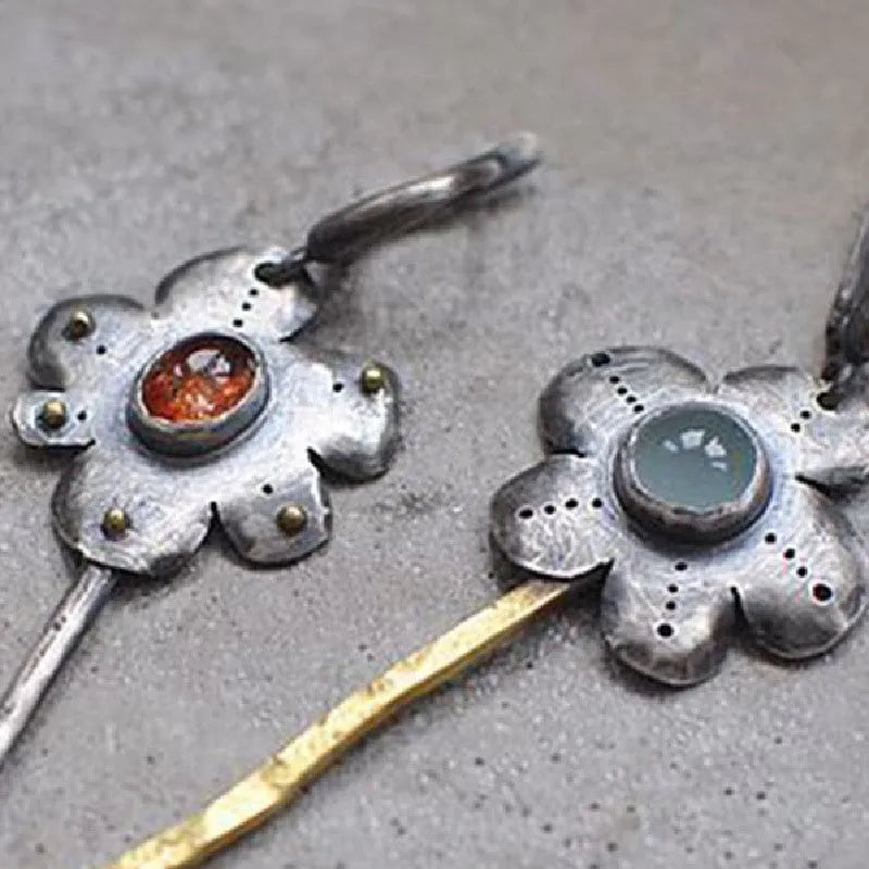 A pair of long, geometric flower-shaped drop earrings with an asymmetric two-tone metallic finish.