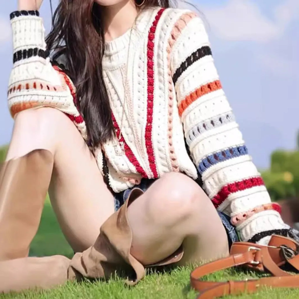 Retro rainbow striped pullover sweater with batwing sleeves on a hanger.