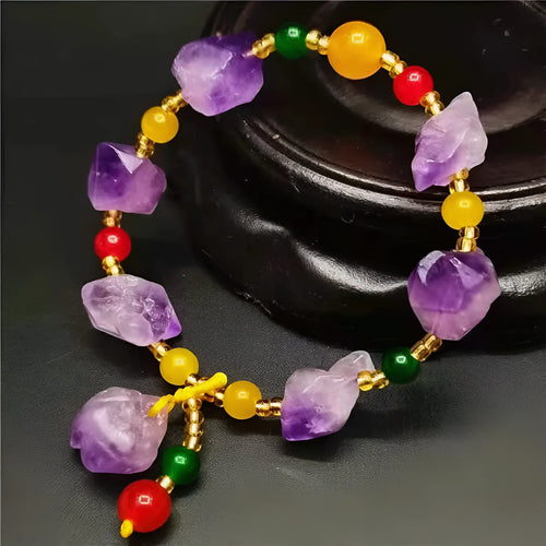 Purple amethyst bracelet with natural shaped beads and a fu character charm on a white background.