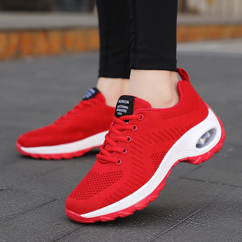 Women's red low-top mesh sneakers with front laces and a flat heel on a white background.